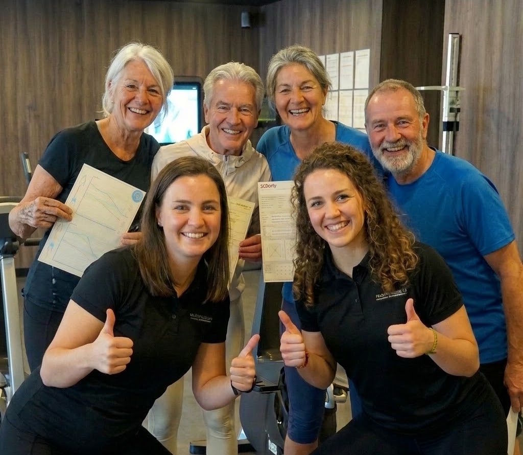 Oudere leden met hun InBody-resultaten en twee coaches