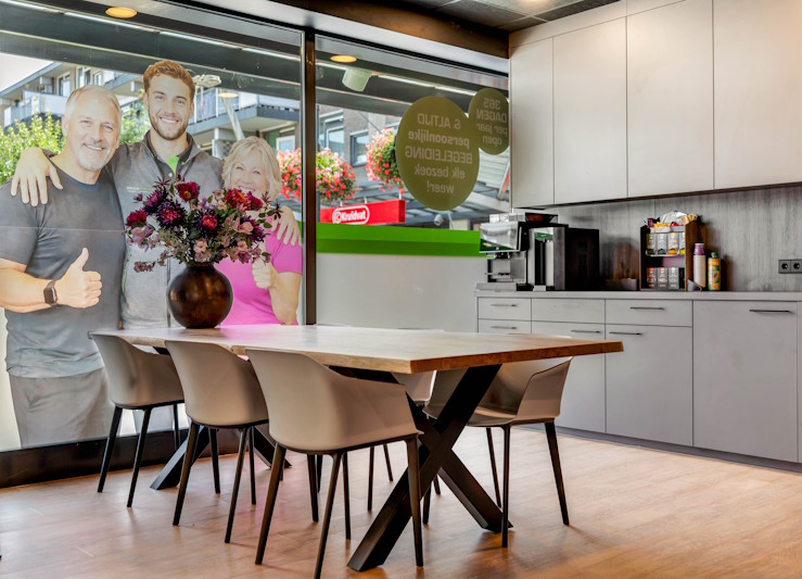Ontvangstruimte met lange tafel en keuken in Happy Bodies Nieuwegein